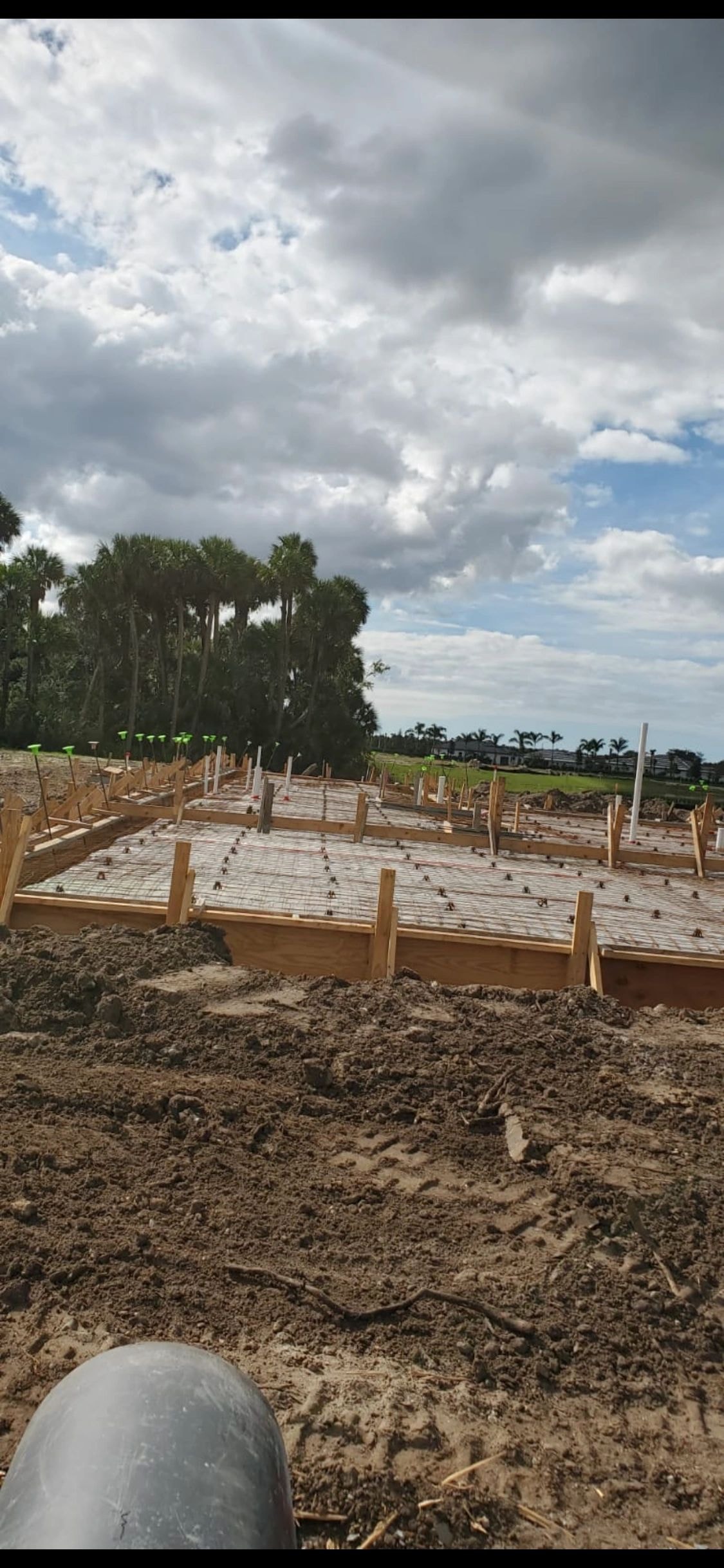 Concrete foundation formwork at a construction site with palm trees